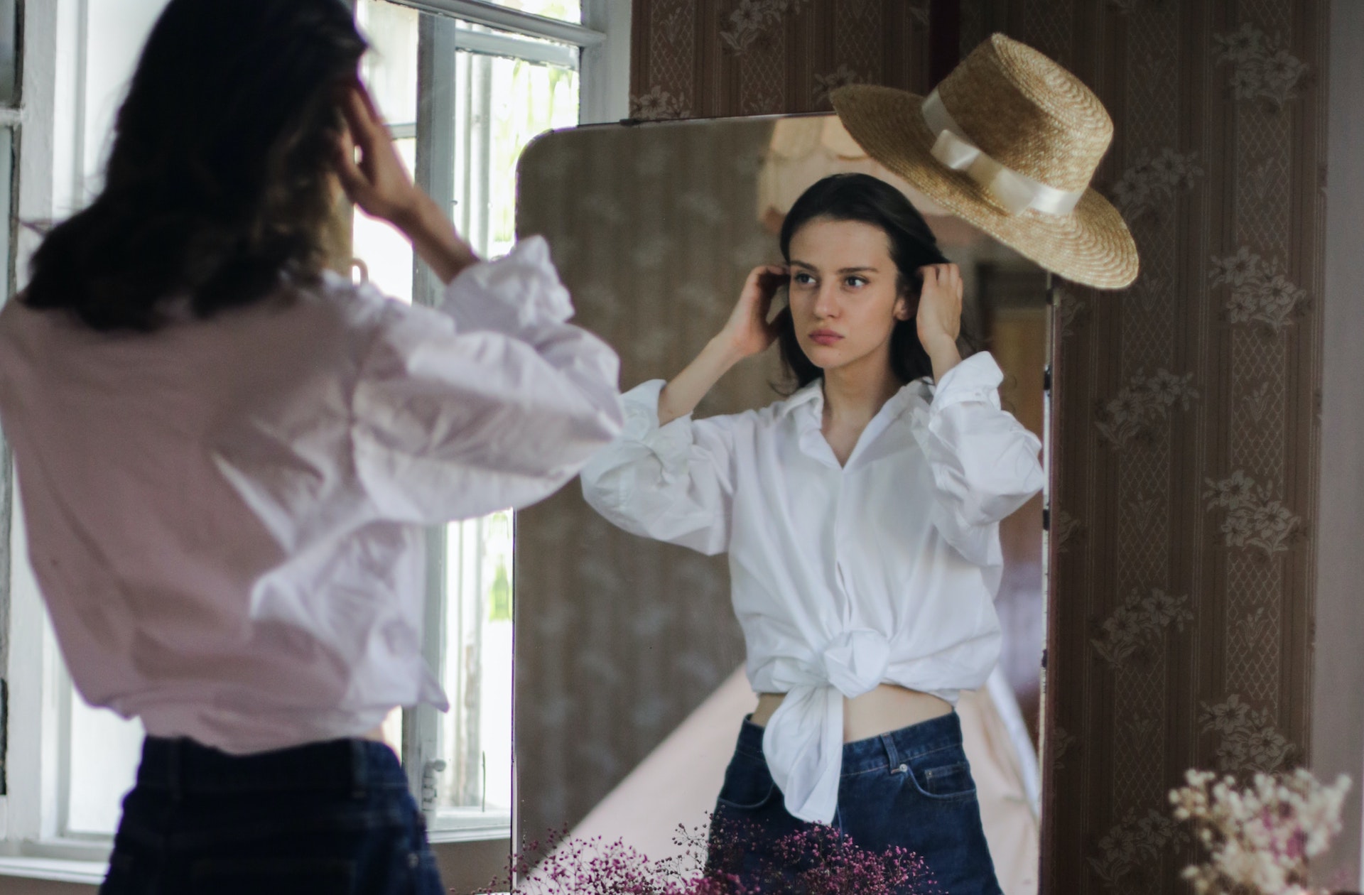 Une jeune femme essaye un jean face à un miroir